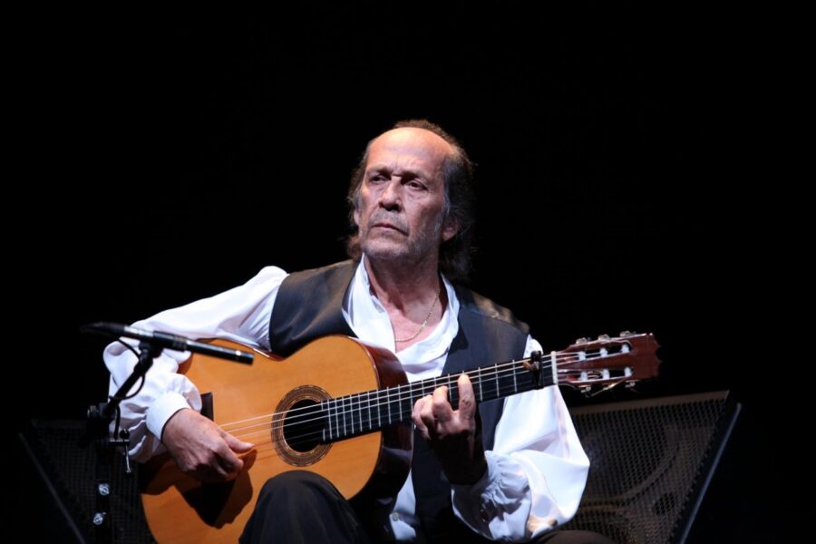 Fotografía de Paco de Lucía tocando la guitarra flamenca. Se muestra concentrado, con los ojos cerrados y el rostro inclinado hacia las cuerdas, transmitiendo la intensidad y el sentimiento de su toque.