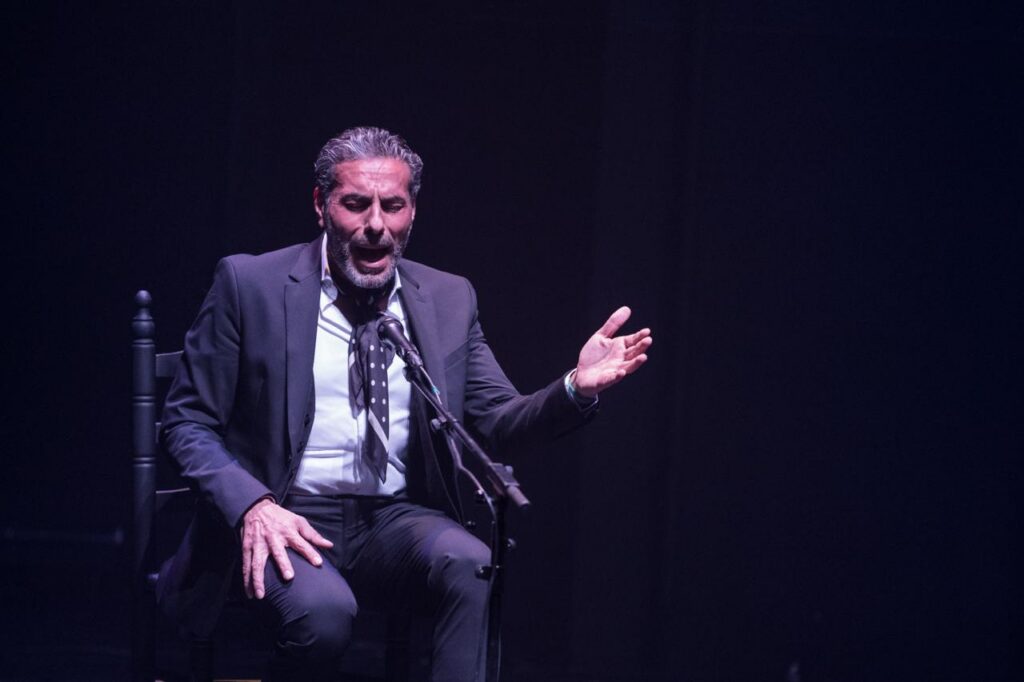 Pedro el Granaíno in a full flamenco singing performance, with his hand extended and the quejío in his voice